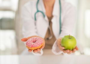 Closeup on doctor giving a choice between apple and donut